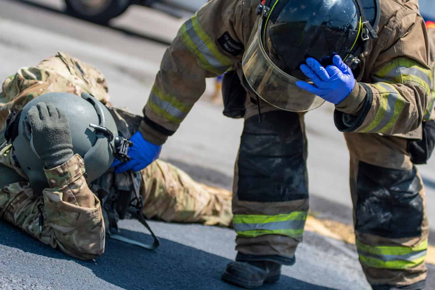 A fire fighter with the Tulsa, Oklahoma Fire Department checks the status of a simulated casualty played by an Oklahoma Army National Guard Citizen-Soldier during pre-accident training at the Oklahoma Army National Guard's Army Aviation Support Facility 2, in an exercise to help prevent military training deaths. 