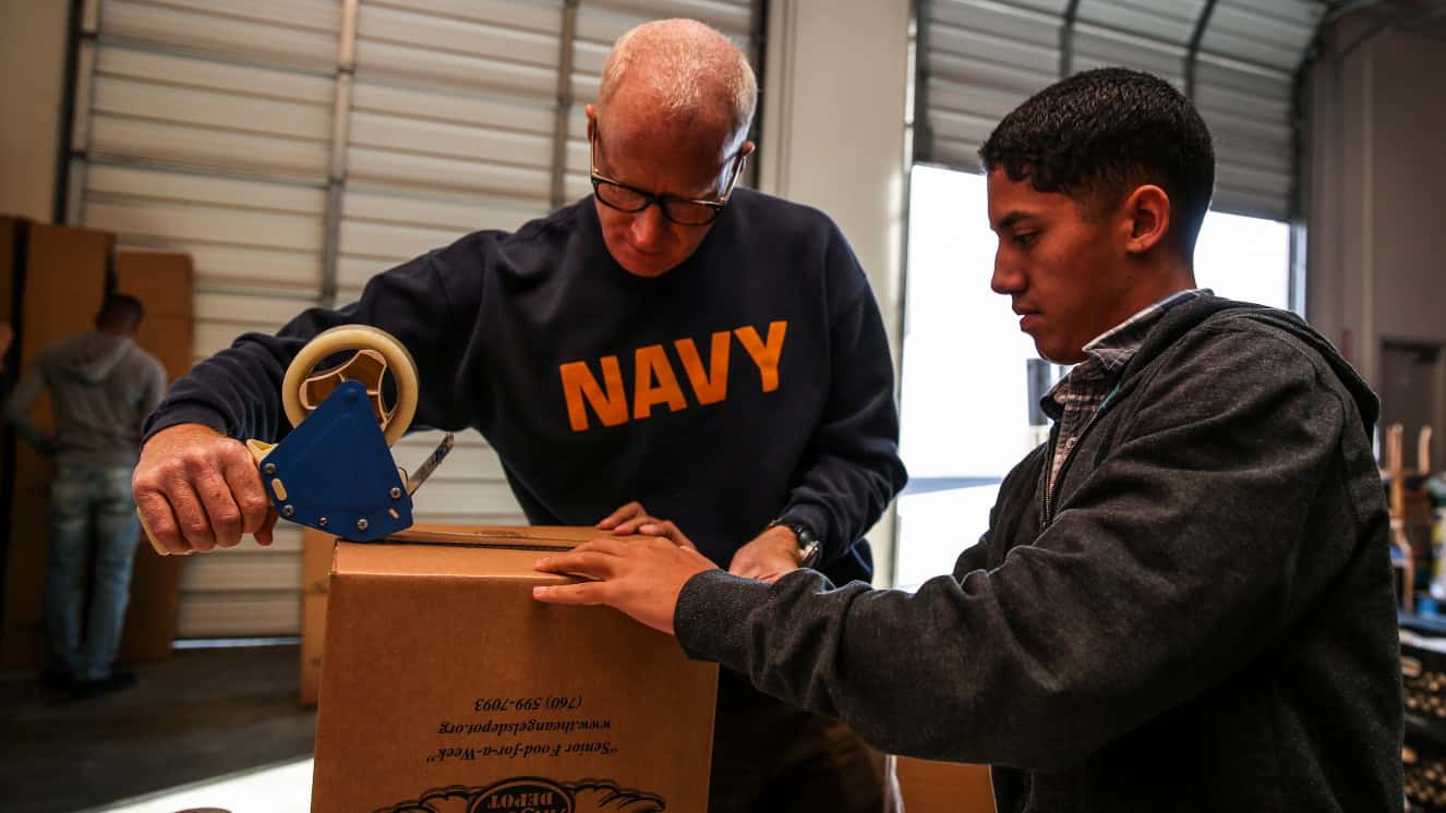 Lieutenant Cmdr. David Dinkins, left, chaplain, and Cpl. Richard Hernandez, data network specialist, both with the 15th Marine Expeditionary Unit, assemble a box during a volunteer event at The Angel's Depot in Vista, Calif. National volunteer week presents many such opportunities for armed forces personnel, civilians, and Veterans.