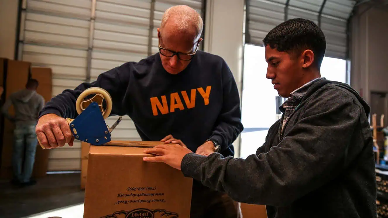 Lieutenant Cmdr. David Dinkins, left, chaplain, and Cpl. Richard Hernandez, data network specialist, both with the 15th Marine Expeditionary Unit, assemble a box during a volunteer event at The Angel's Depot in Vista, Calif. National volunteer week presents many such opportunities for armed forces personnel, civilians, and Veterans.