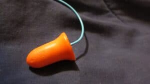 Orange earplugs sitting on top of a grey shirt in light of the 3m earplug lawsuit.