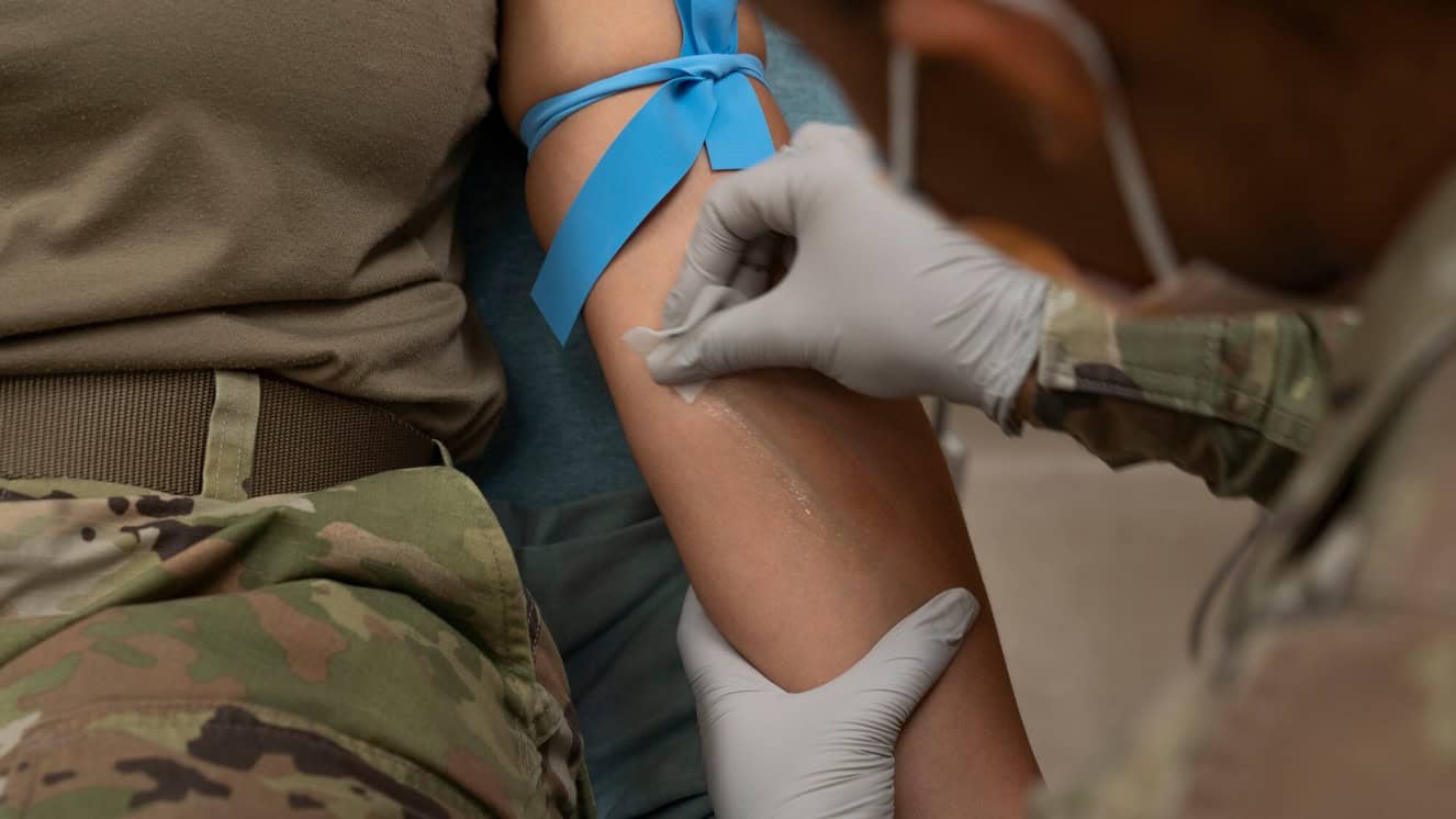U.S. Army Spc. Kristen Casarez, a medic, applies a band aid after applying an intravenous needle containing ketamine in Colorado Springs into U.S. Army Pfc. Stephen Capizzi.