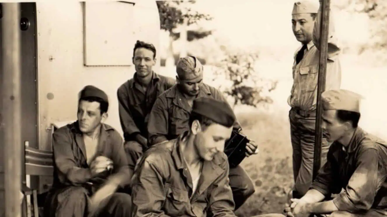 Troops who received order no 227 from Stalin gather together under a tent to look at a photograph.