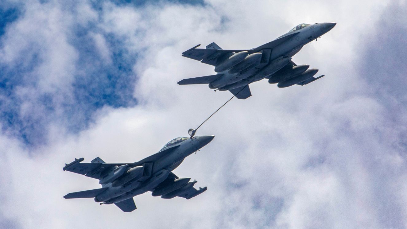 An F/A-18E Super Hornet from the “Kestrels” of Strike Fighter Squadron (VFA) 137 refuels an E/A-18G Growler from the “Cougars” of Electronic Attack Squadron (VAQ) 139 conduct an aerial refueling during flight operations near the aircraft carrier USS Nimitz (CVN 68).