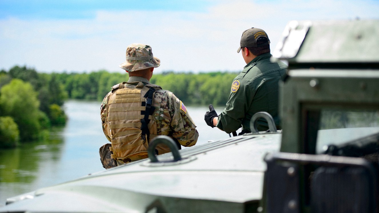 A Texas Guardsmen and a Customs and Border Patrol agent from the Texas National Guard discuss the lay of the land on the shores of the Rio Grande River.