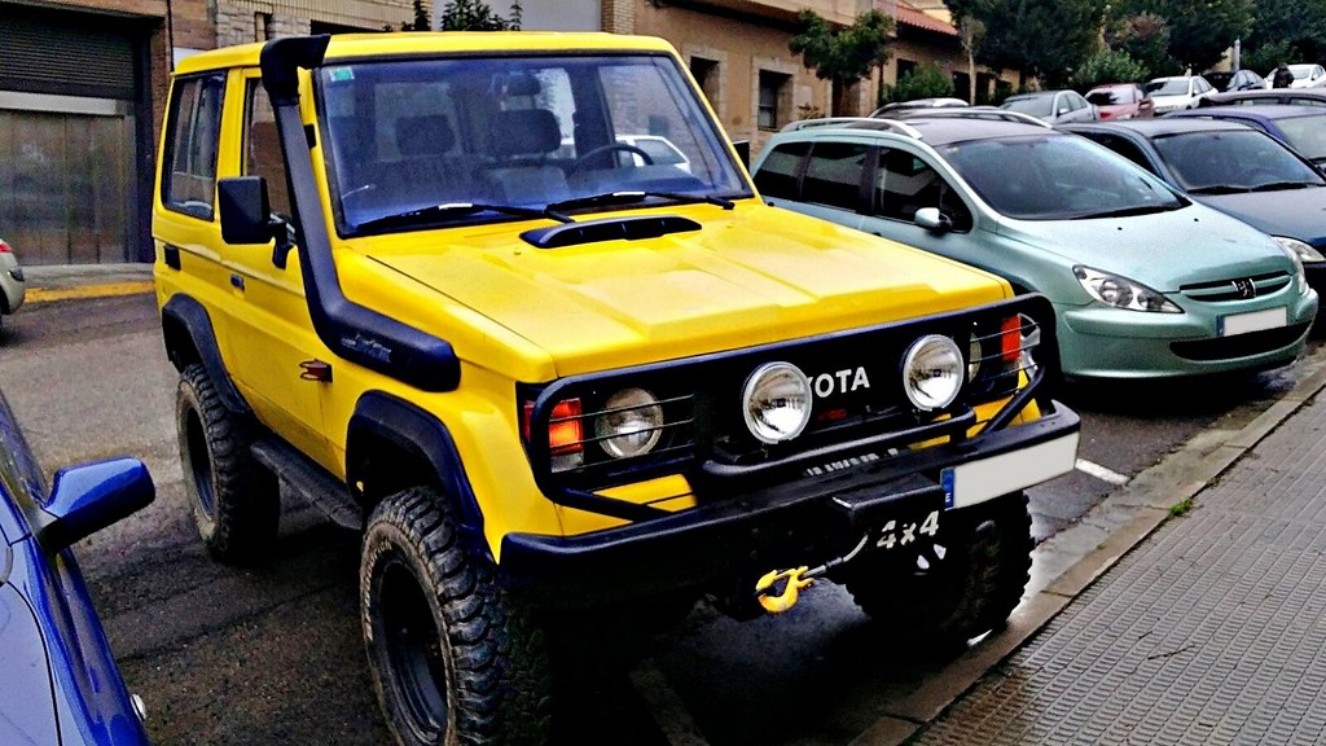 Yellow Toyota Land Cruiser in a parking lot.