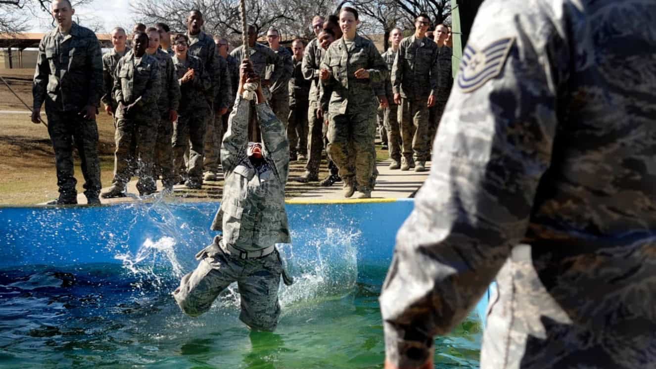 A basic trainee skims her knees on a cold water pool while completing the obstacle course for Air Force recruitment on Lackland AFB, San Antonio, Texas.