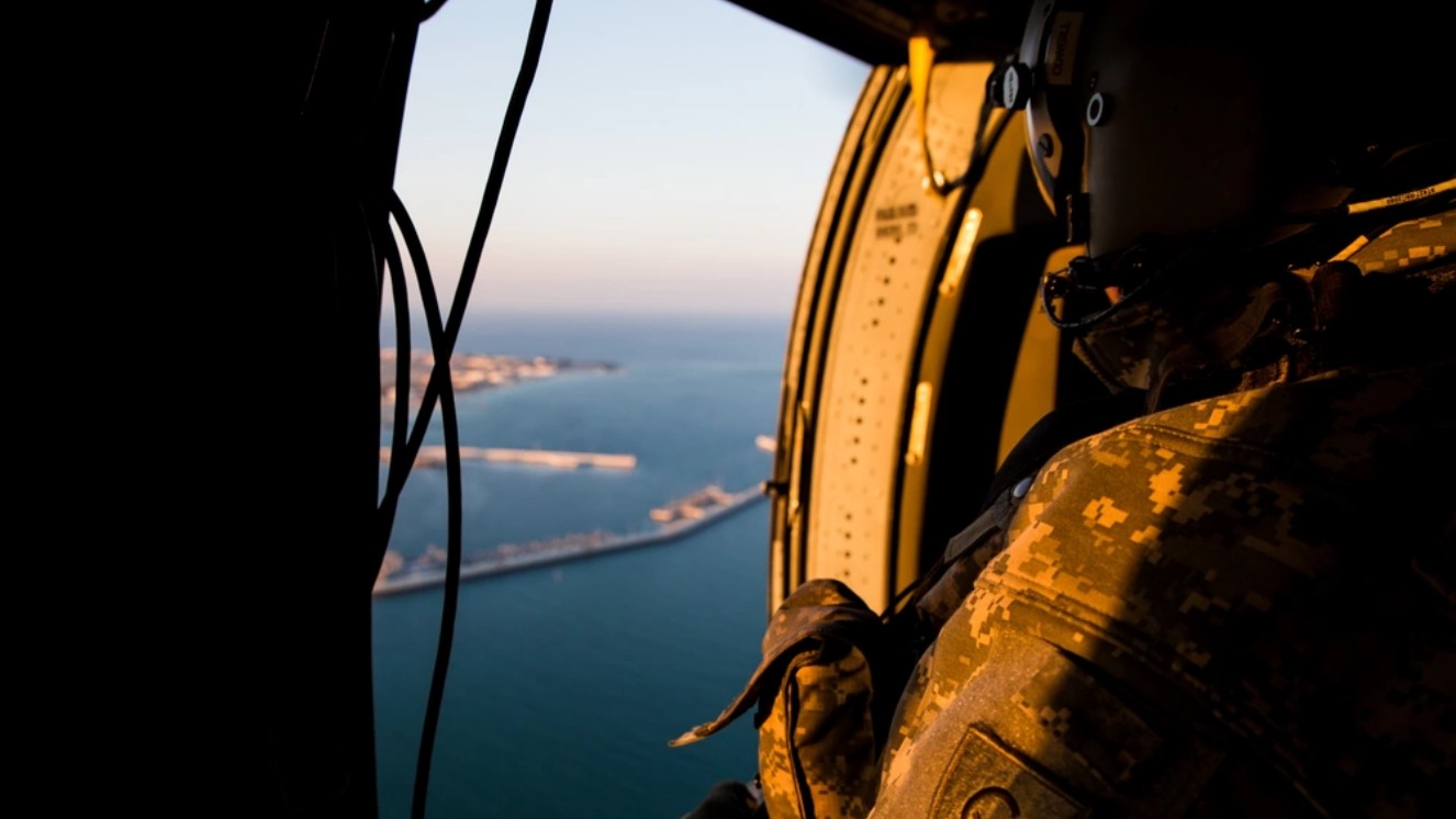Sgt. Ron Cowgill, from Dover, Del., now a crew chief with 3rd Battalion, 238th General Support Aviation Battalion, Minnesota National Guard, looks out to sea during a UH-60 Blackhawk flight on Feb. 6, 2014,