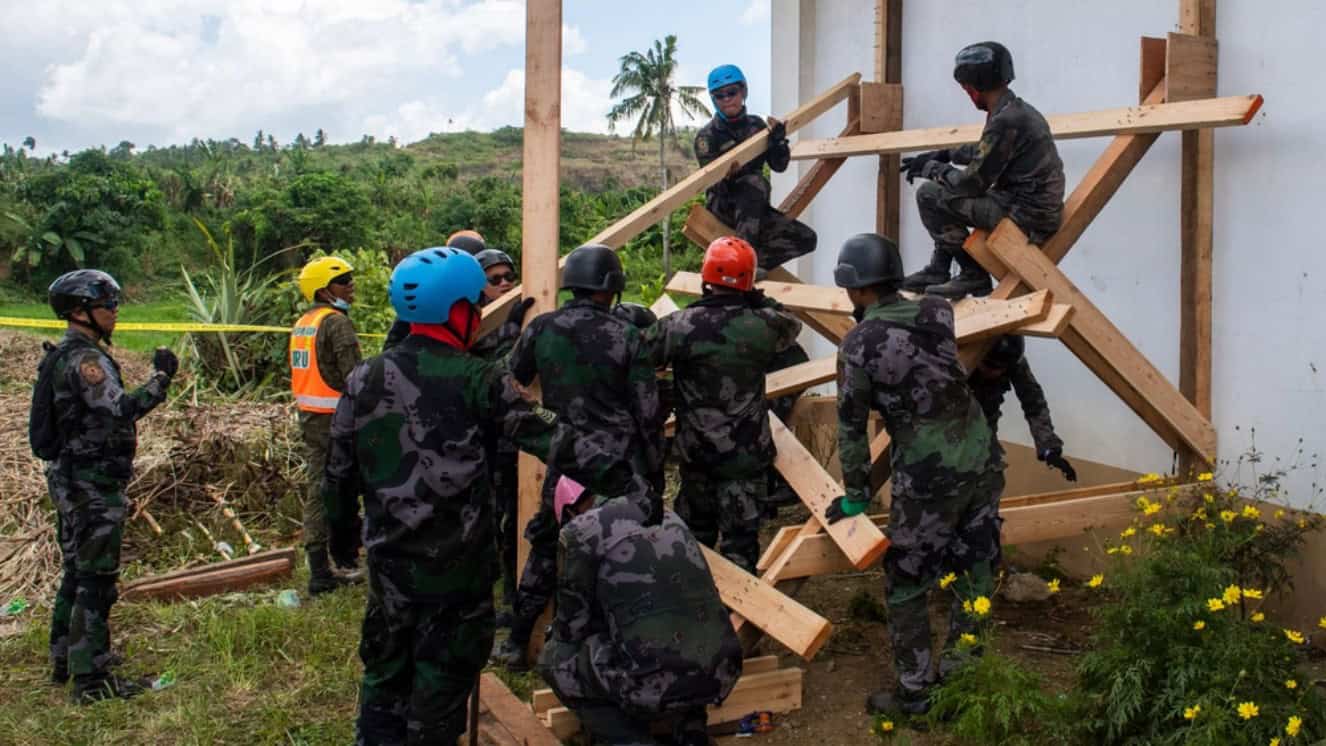 Members of the Philippine National Police construct shoring to reinforce a building during a field training exercise at the Tacloban North Public Market that simulated a response to a notional 8.5-magnitude Philippines earthquake.