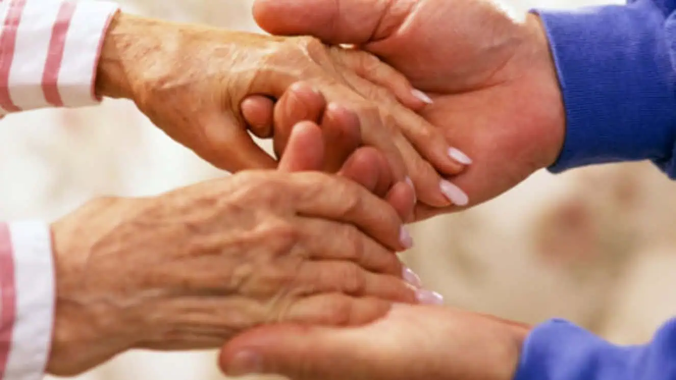 VA family caregiver and Vet holding hands.