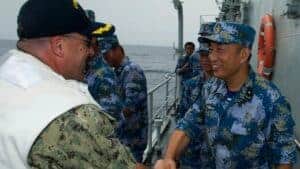 Chinese Sailor and American Sailor shaking hands aboard a Chinese military aircraft.