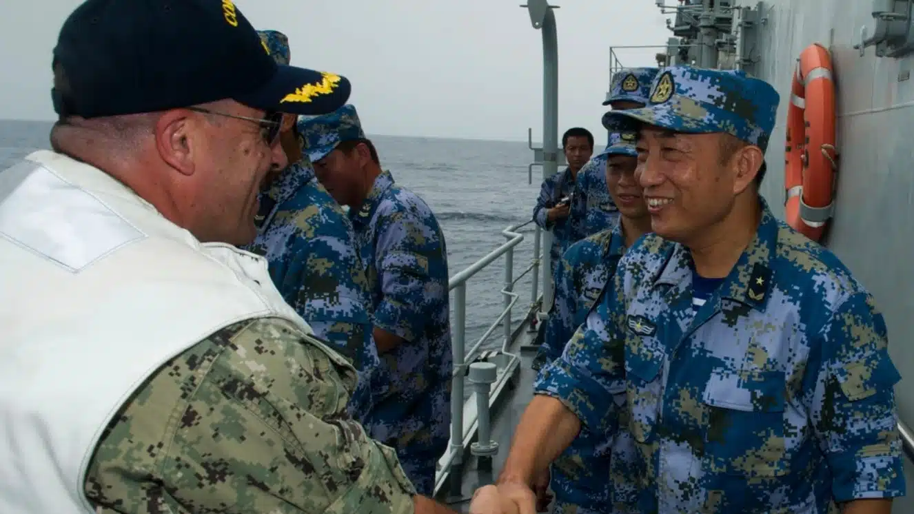 Chinese Sailor and American Sailor shaking hands aboard a Chinese military aircraft.