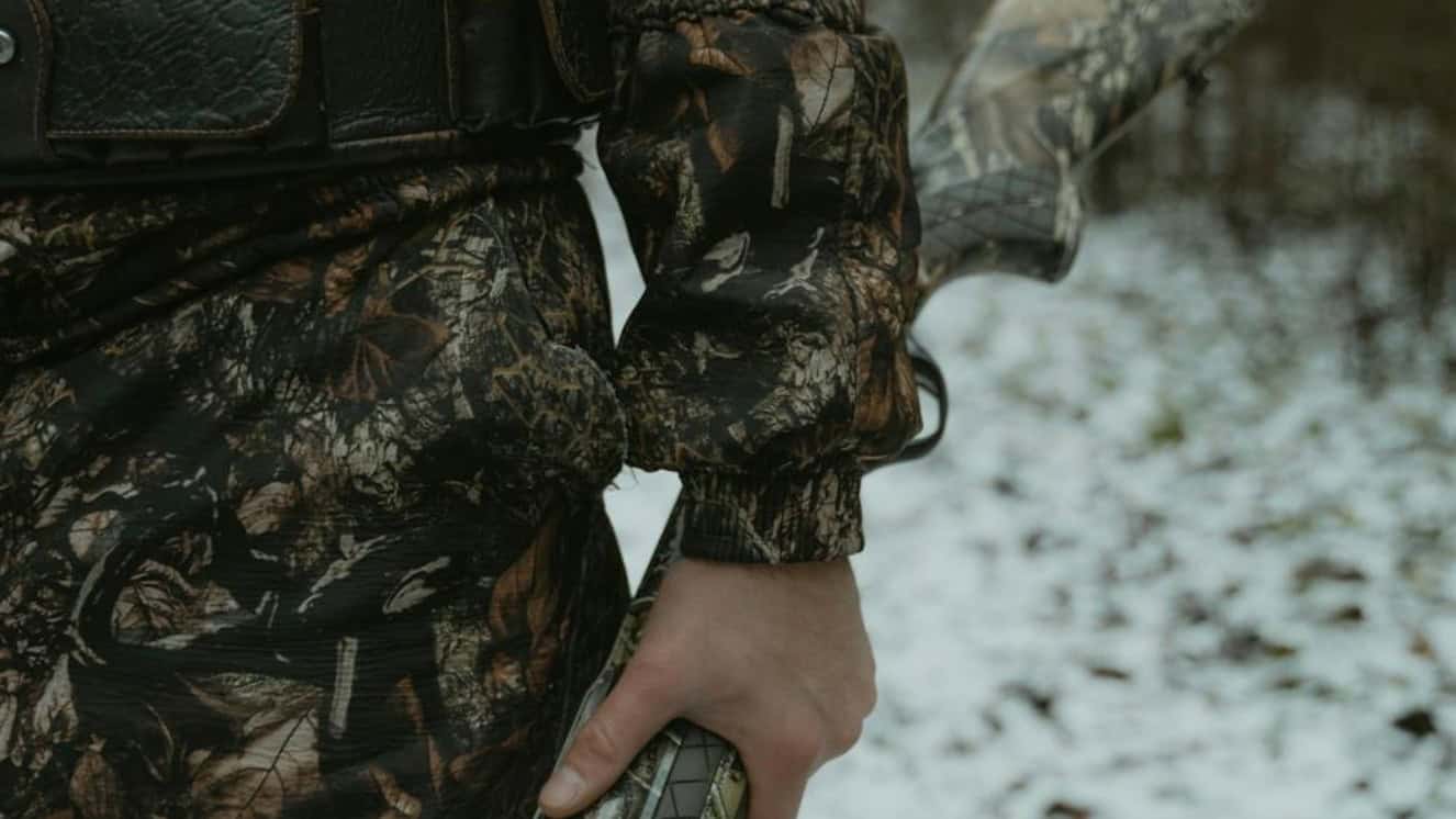 Man holding a gun using a hunting trip guide.