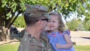 Military brat meaning has many facets as soldier holds his little girl.