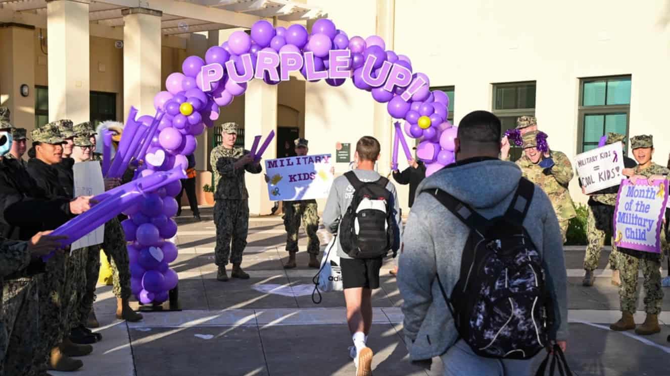 Service members cheer on students from Department of Defense Education Activity Schools Sigonella as they arrive during Purple Up Day as part of Month Of Military Child celebration, April 19, 2022.