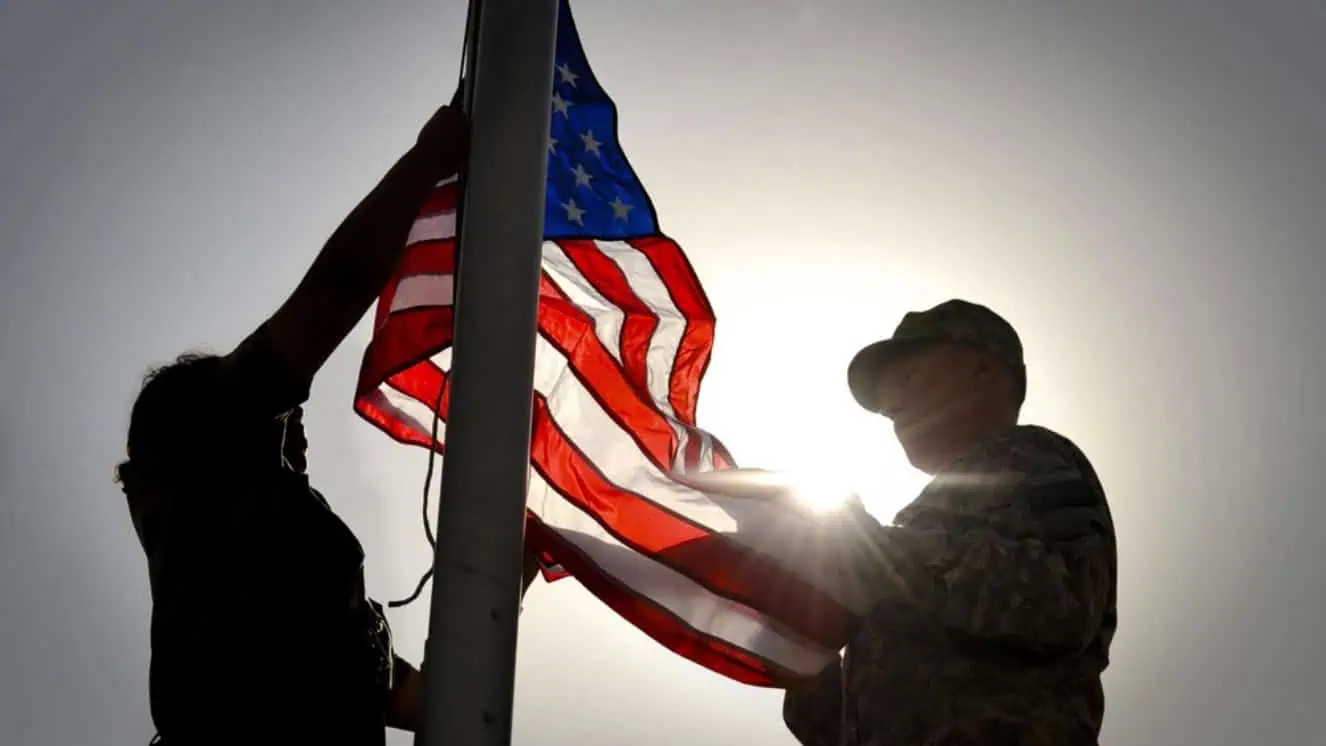 Soldiers raising the American flag, as we look back at American flags through history.