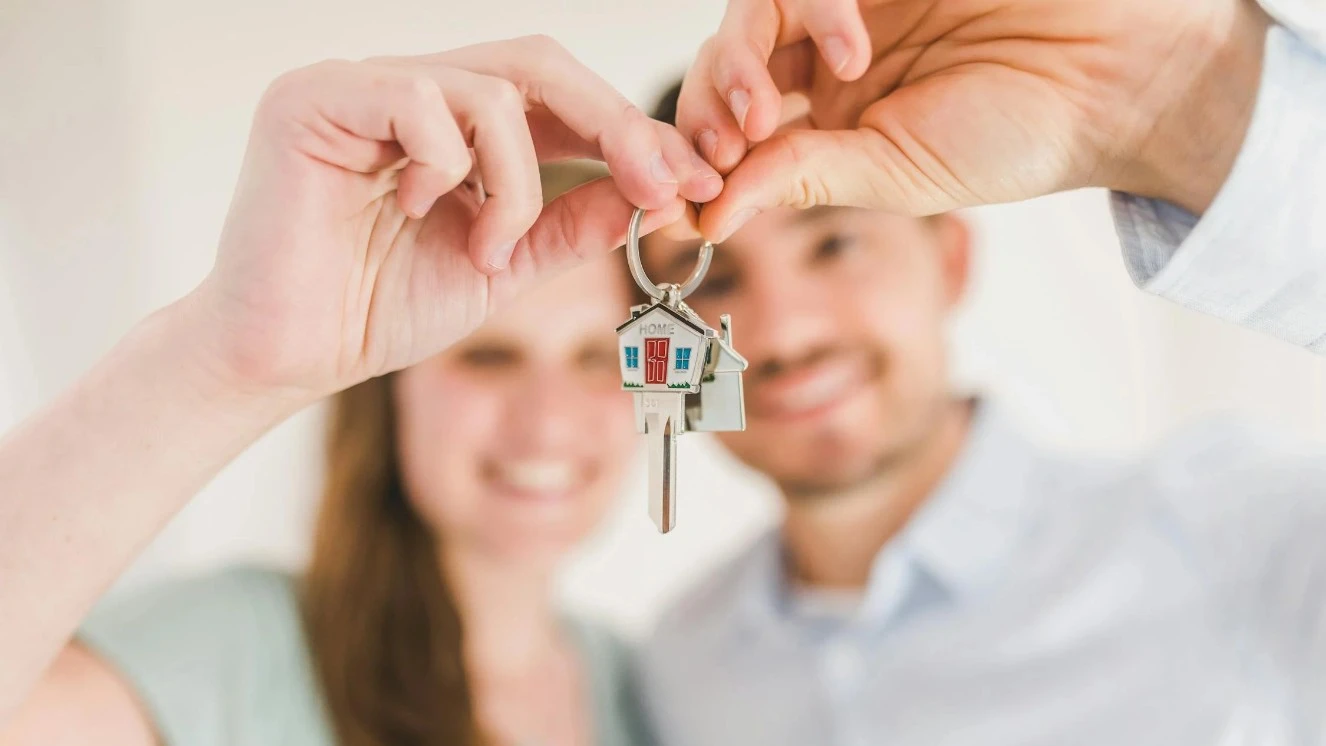 A first time home buyer couple holding a set of house keys.