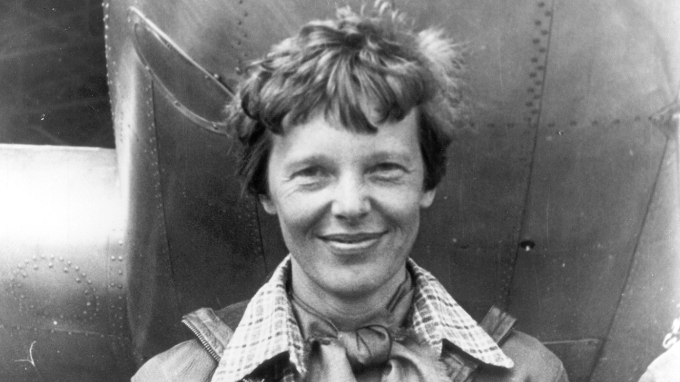 Amelia Earhart standing by a plane as we celebrate Amelia Earhart day.