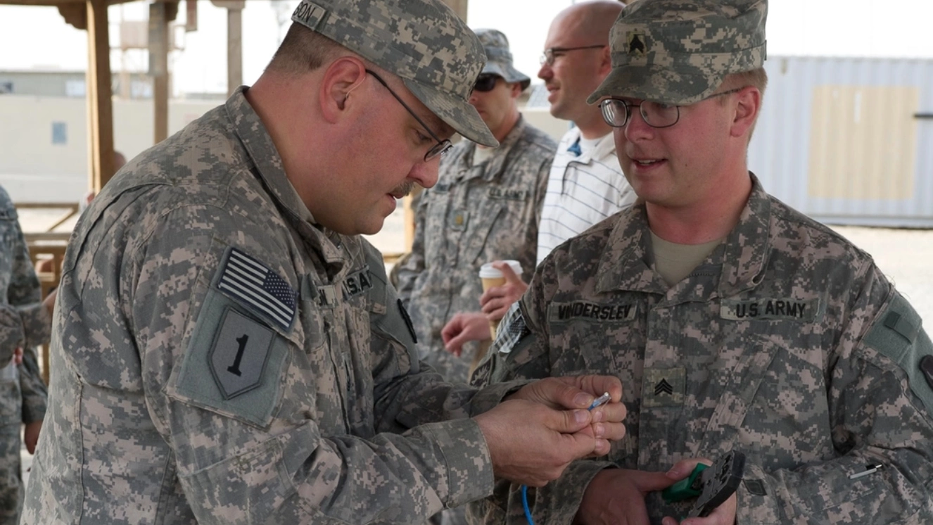 Army Master Sgt. Daniel Swanson, information systems operator-analyst non-commissioned officer in charge and Spc. Chris Vinderslev, information systems operator-analyst with 134th Brigade Support Battalion Signal Corps, patch in a satellite link for the brigade commander's Minnesota Military Radio Hour interview at Camp Virginia, Kuwait, Nov. 13, 2011.