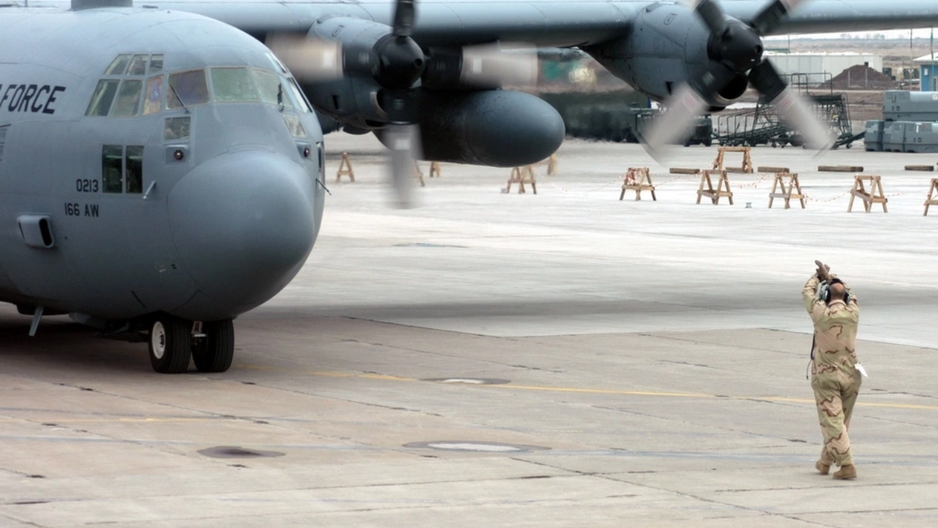 Crew chief Tech. Sgt. Robert Rothove, signals a C-130 Hercules cargo aircraft to come to a stop at Karshi-Khanabad Air Base, Uzbekistan, on Jan. 17, 2005, in support of Operation Enduring Freedom.