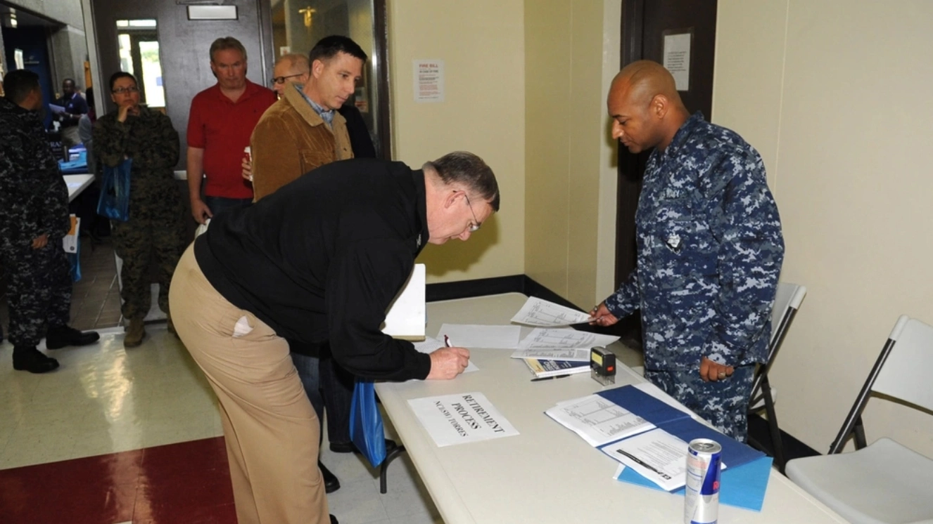 Personnel Specialist 2nd Class Jeremy Honeywood (right) checks-in arriving attendees for the Reserve Retirement Benefit Seminar at Navy Operational Support Center San Diego. Approximately 120 Navy Reservists, Coastguardsmen, retirees and their spouses participated in the one-day event to learn about numerous veterans benefits, meet benefit specialists and prepare for retirement with Veteran benefit checks.