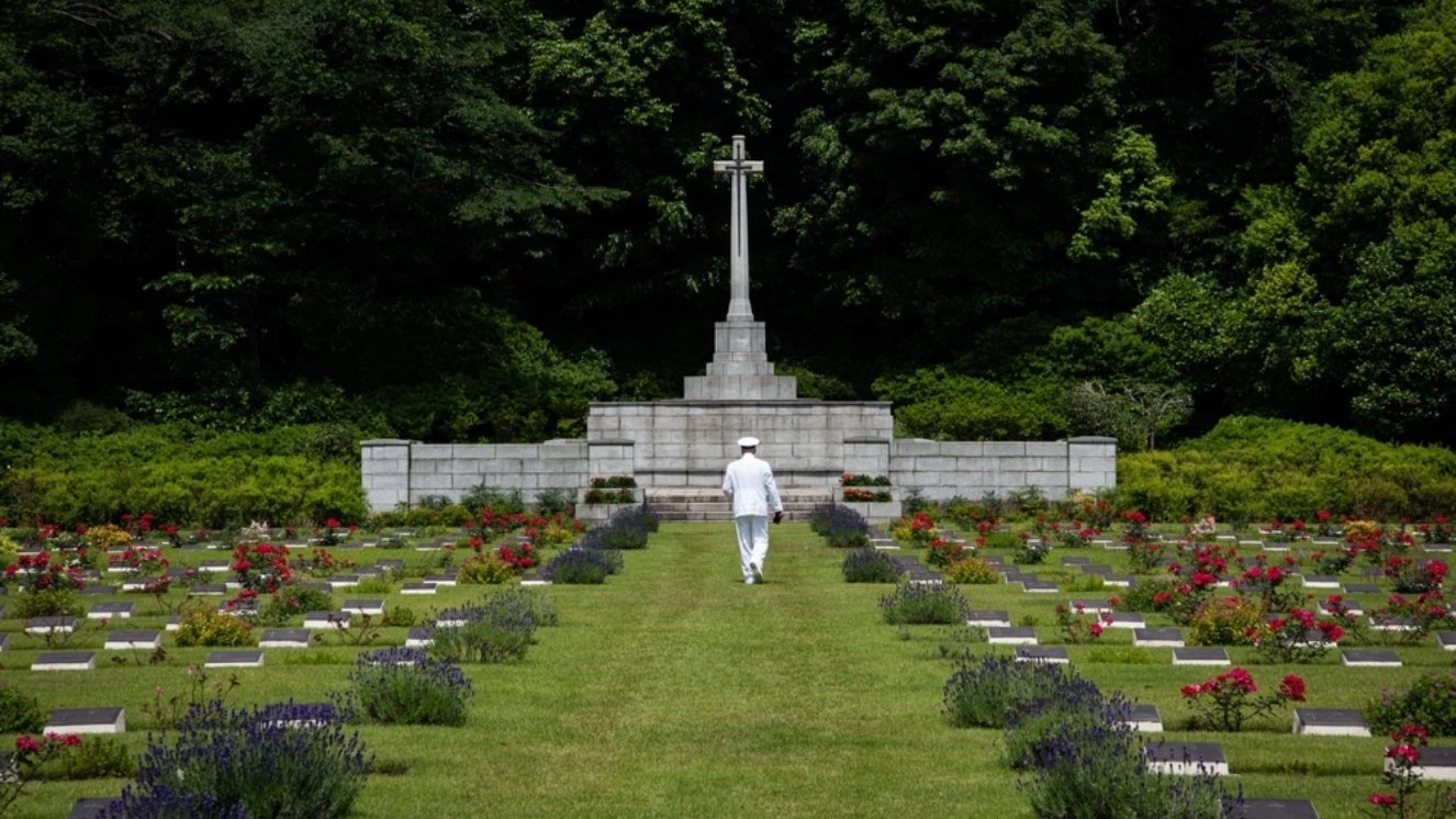 A U.S. Sailor walks through the British Commonwealth War Graves Commission Cemetery before the Veterans of Foreign Wars Day observance ceremony. For more than 75 years, CFAY has provided, maintained, and operated base facilities and services in support of the U.S. 7th Fleet's forward-deployed naval forces, tenant commands, and thousands of military and civilian personnel and their families.